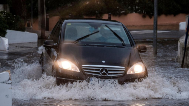 Un coche transita una calle inundada de Ibiza