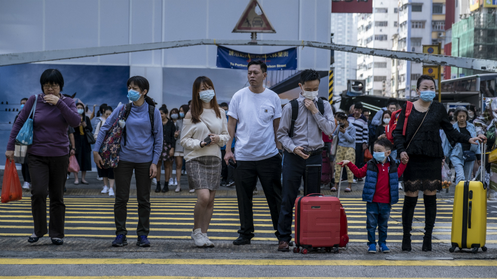 Varias personas usan mascarilla en un paso de peatones de Hong Kong,...