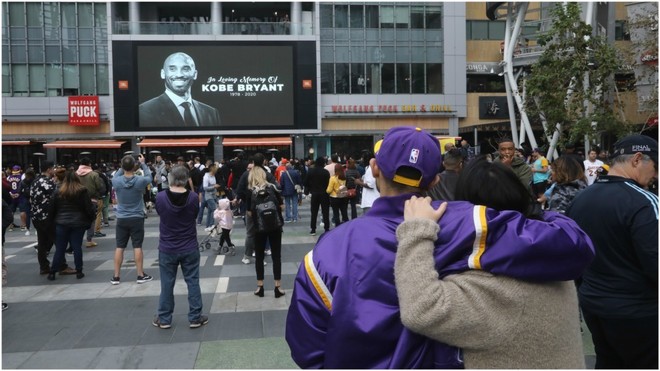 Aficionados se abrazan ante la imagen de Kobe Bryant