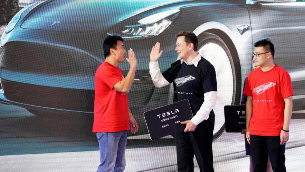 Elon Musk, presidente de Tesla, choca la mano con dos clientes chinos...
