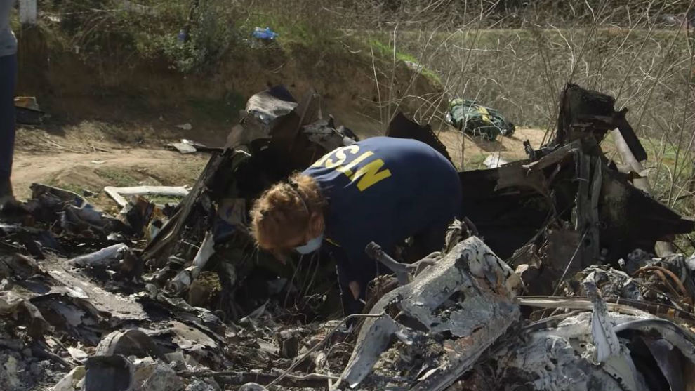 An agent searches for evidence at the crash site.