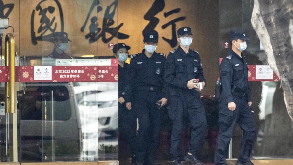 Varios policas chinos salen de un establecimiento.