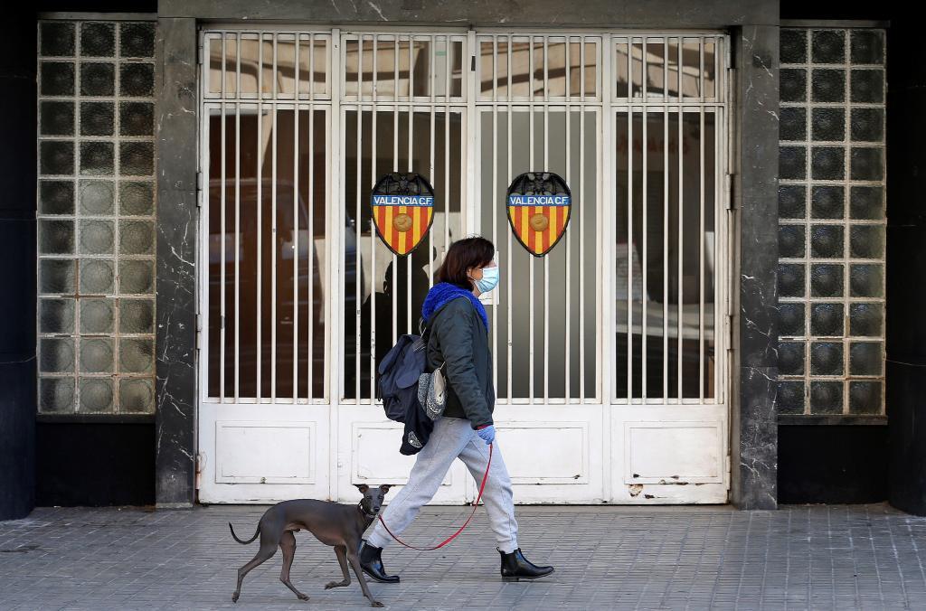 Una mujer pasea su perro por la puerta de Mestalla.
