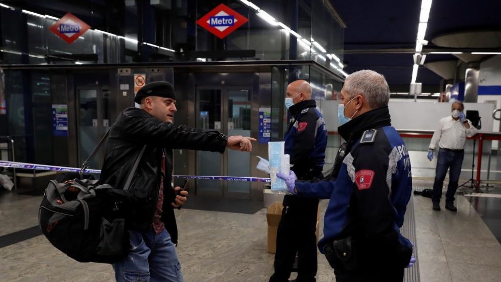 Un agente de la Polica Municipal de Madrid entrega una mascarilla a...