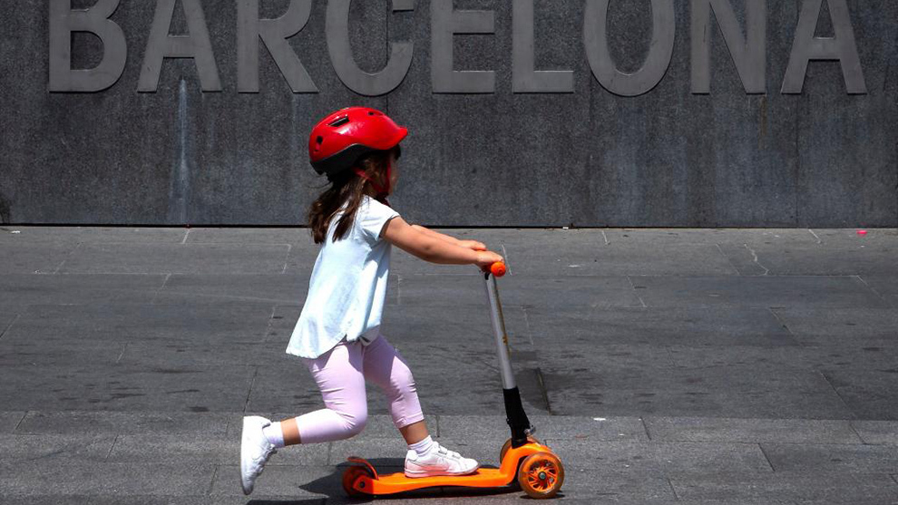 Una nia pasea con un patinete por el centro de Barcelona.