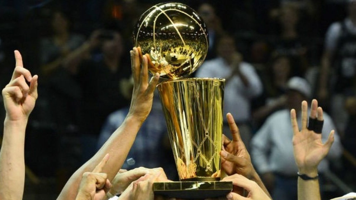 El trofeo de la campen de la NBA, sujetado por varios jugadores.