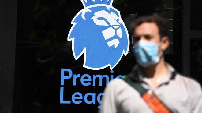 Una persona con mascarilla ante el logo de la Premier.