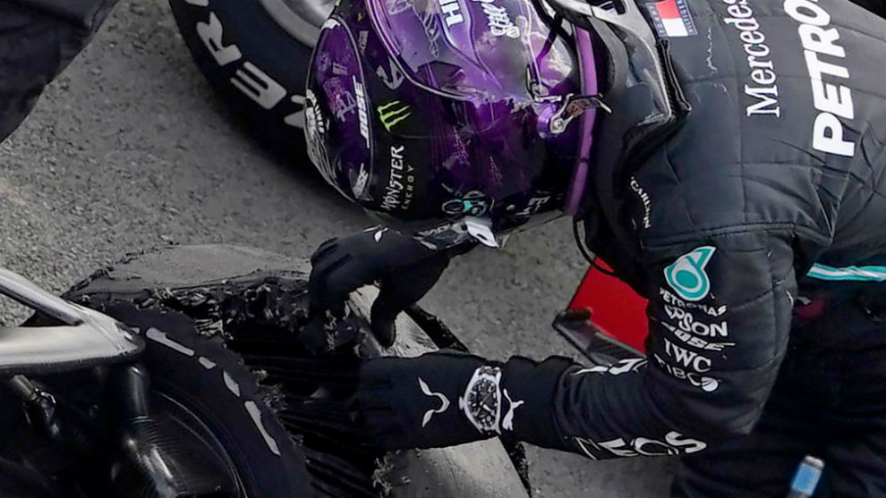 Lewis Hamilton examina la rueda desllantada con la que pudo cruzar la...