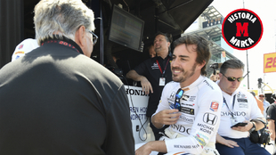 Mario Andretti, de espaldas, charla con Fernando Alonso.