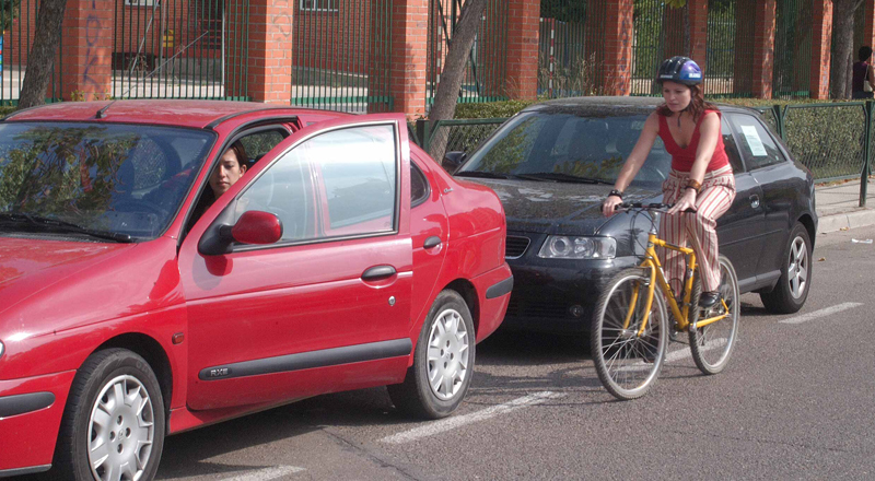 Un conductor abre la puerta de su coche sin advertir la presencia de una ciclista.