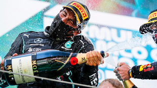 Hamilton celebra un triunfo en el podio, con Verstappen al lado.