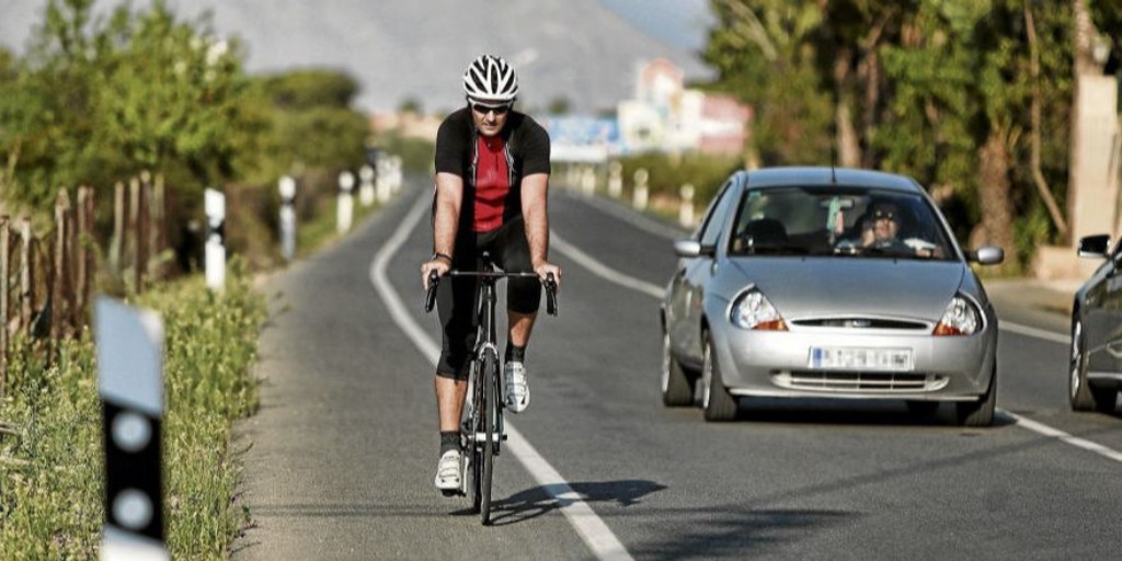 Un coche adelanta a un ciclista en carretera convencional.