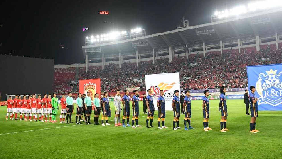 Los onces de Guangzhou FC y Guangzhou City escuchan el himno en la previa del partido inaugural de la Superliga china