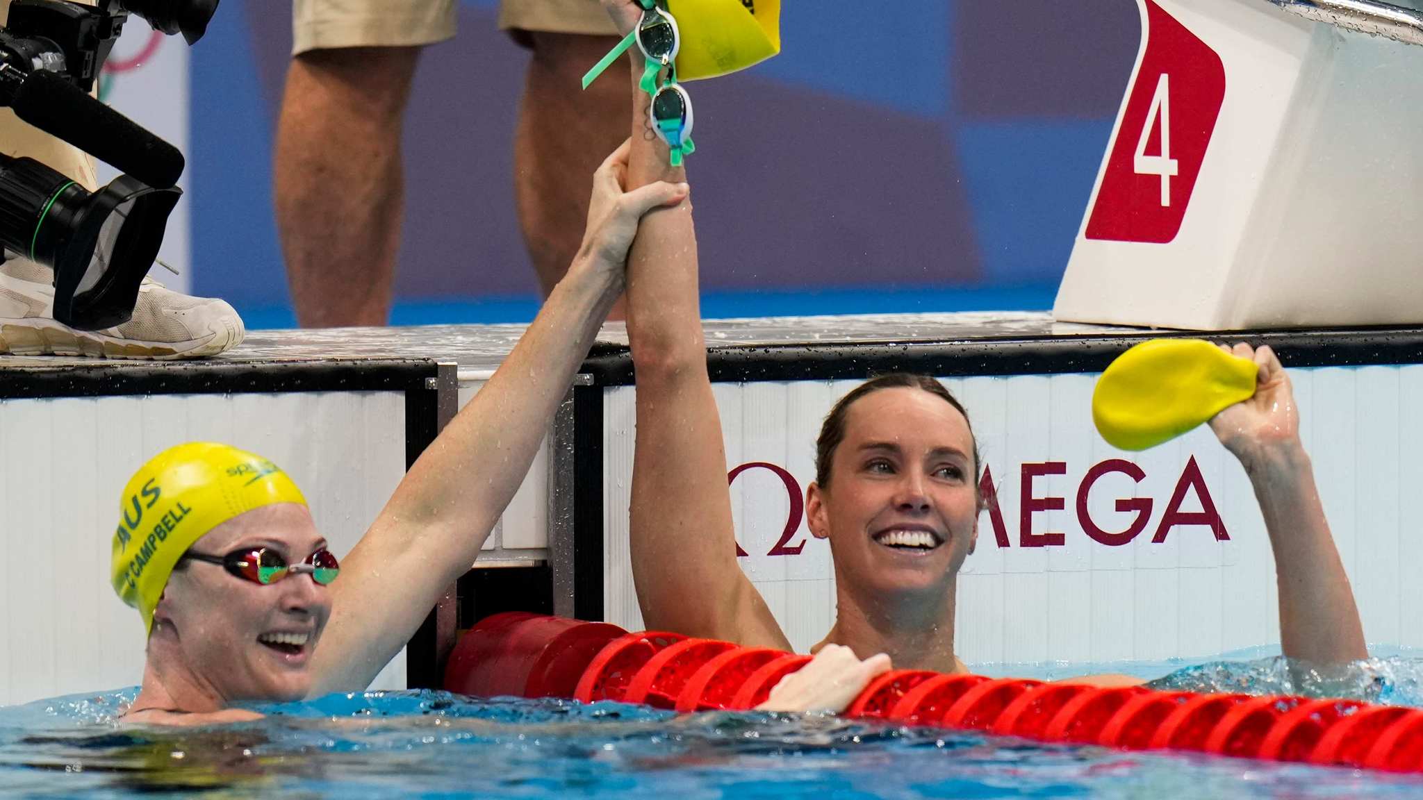 Cate Campbell, bronce, levanta el brazo de Emma McKeon, ganadora ade los 100 libre