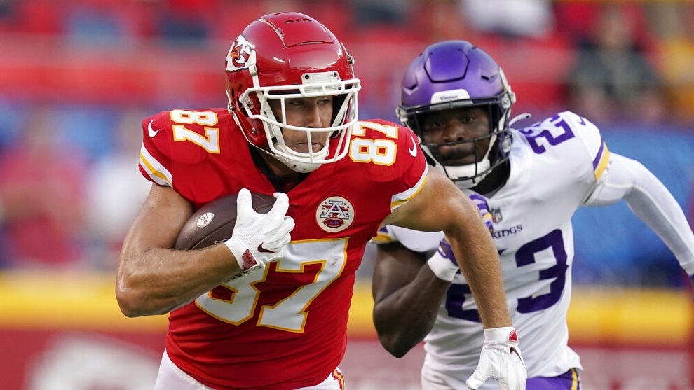 Travis Kelce (87) runs with the ball as Xavier Woods (23) defends.