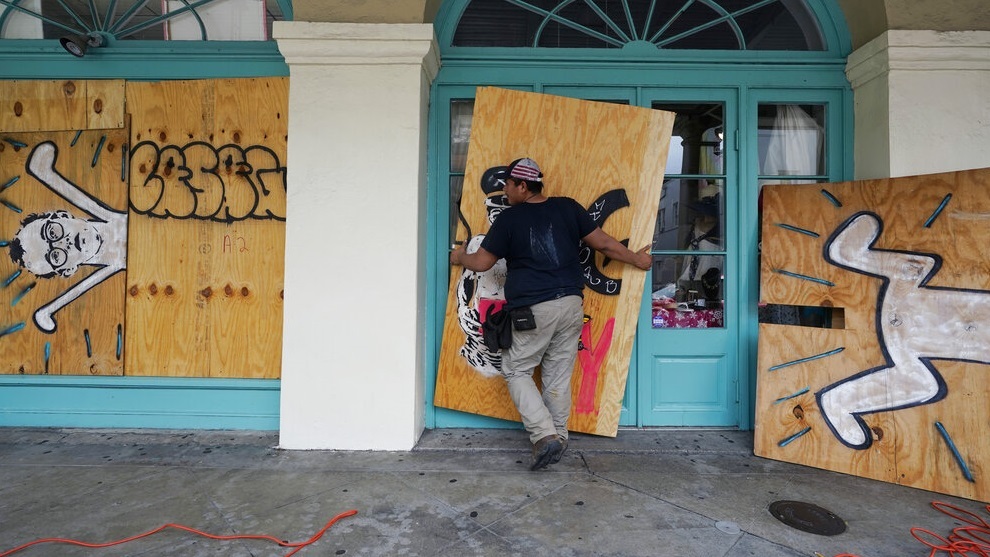 Workers attach protective plywood to windows and doors of a business in New Orleans.