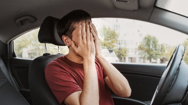 Un conductor se frota la cara con las manos para combatir el cansancio.