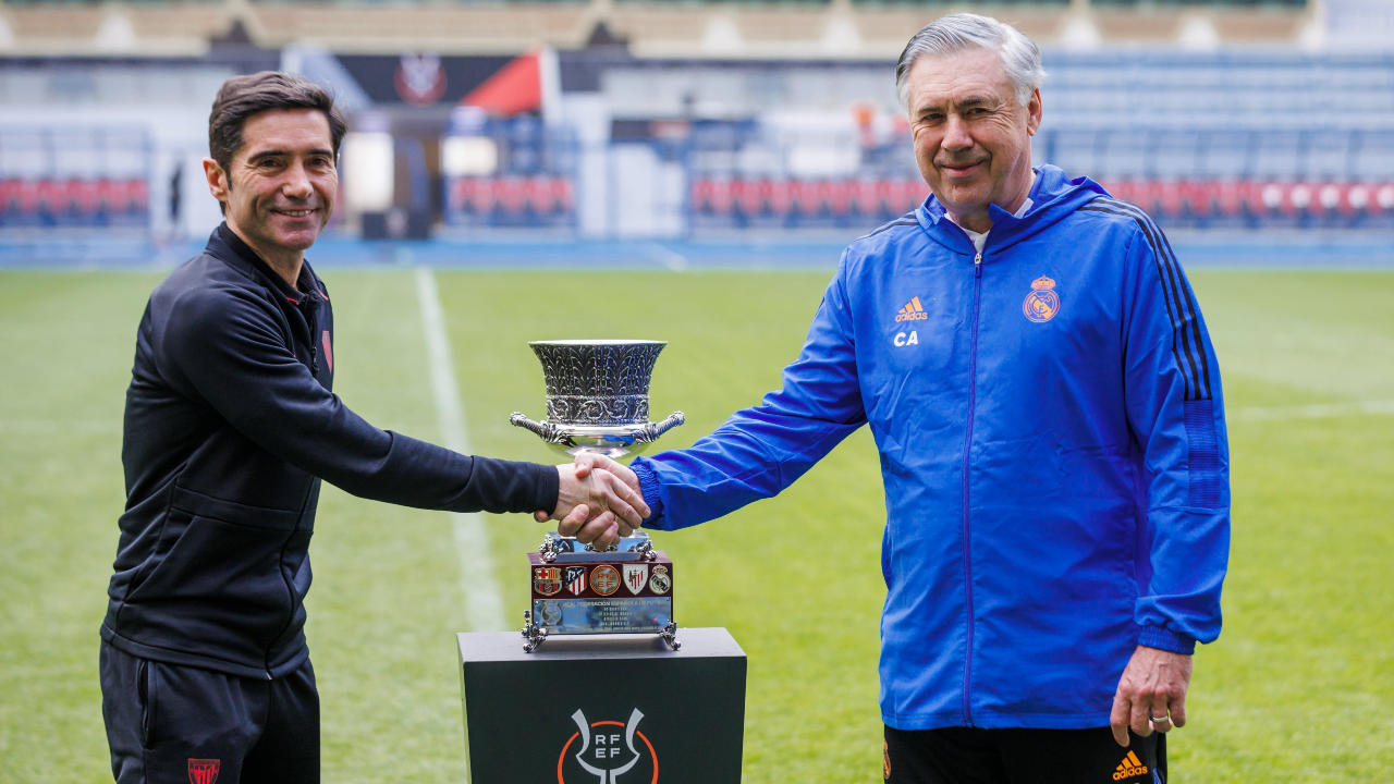 Marcelino and Ancelotti shake hands with the Super Cup trophy in the background.
