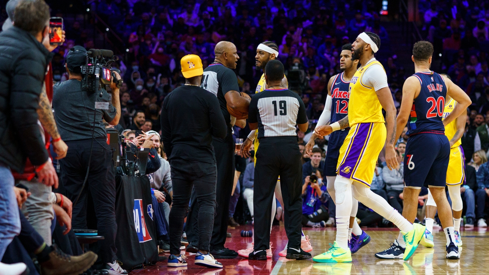 Los Angeles Lakers Carmelo Anthony, top center, is held back by officials after having a word with a fan in the stands during the second half of an NBA basketball game against the Philadelphia 76ers