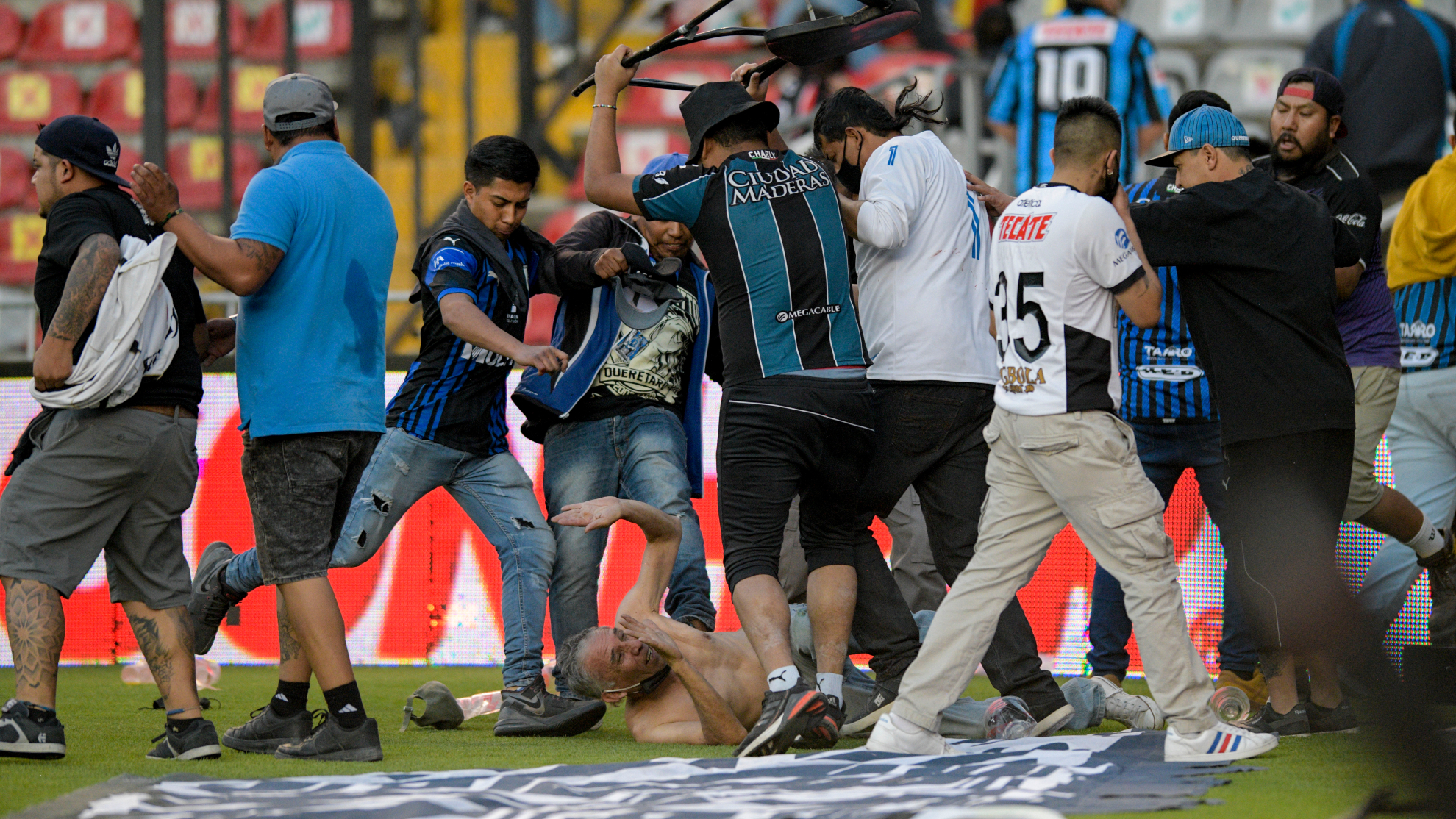 Unos ultras del Querétaro patean a uno del Atlas en pleno césped.