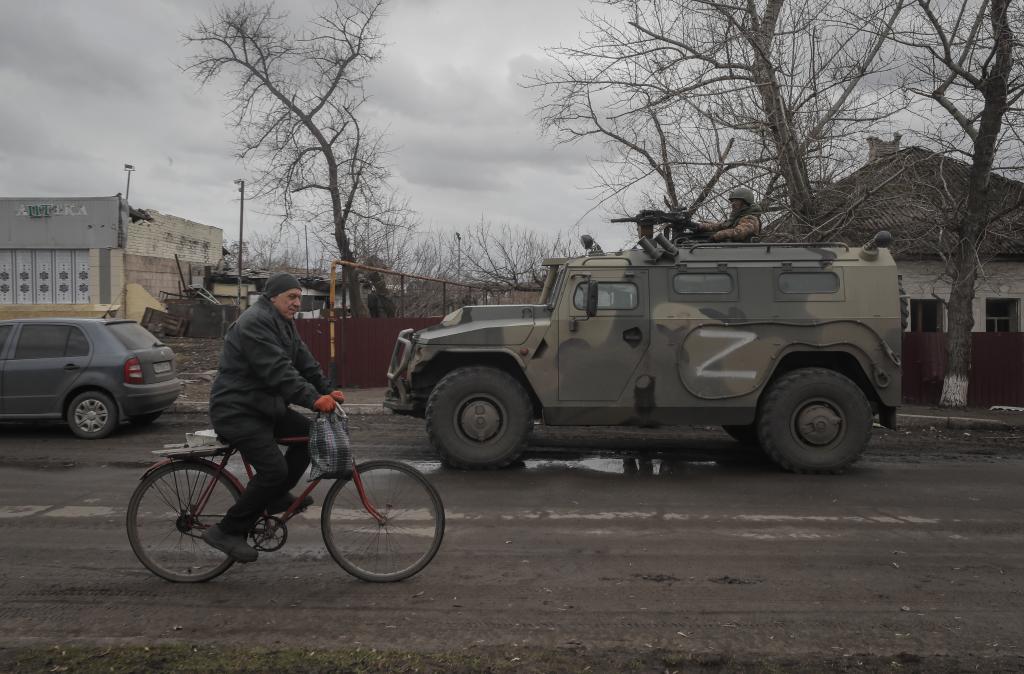Un civil cruza ante un vehculo blindado ruso en una zona ocupada por estos