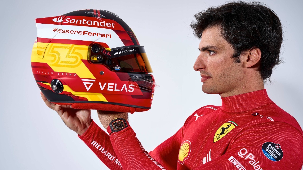 Carlos Sainz se mira en su casco con el uniforme de Ferrari.