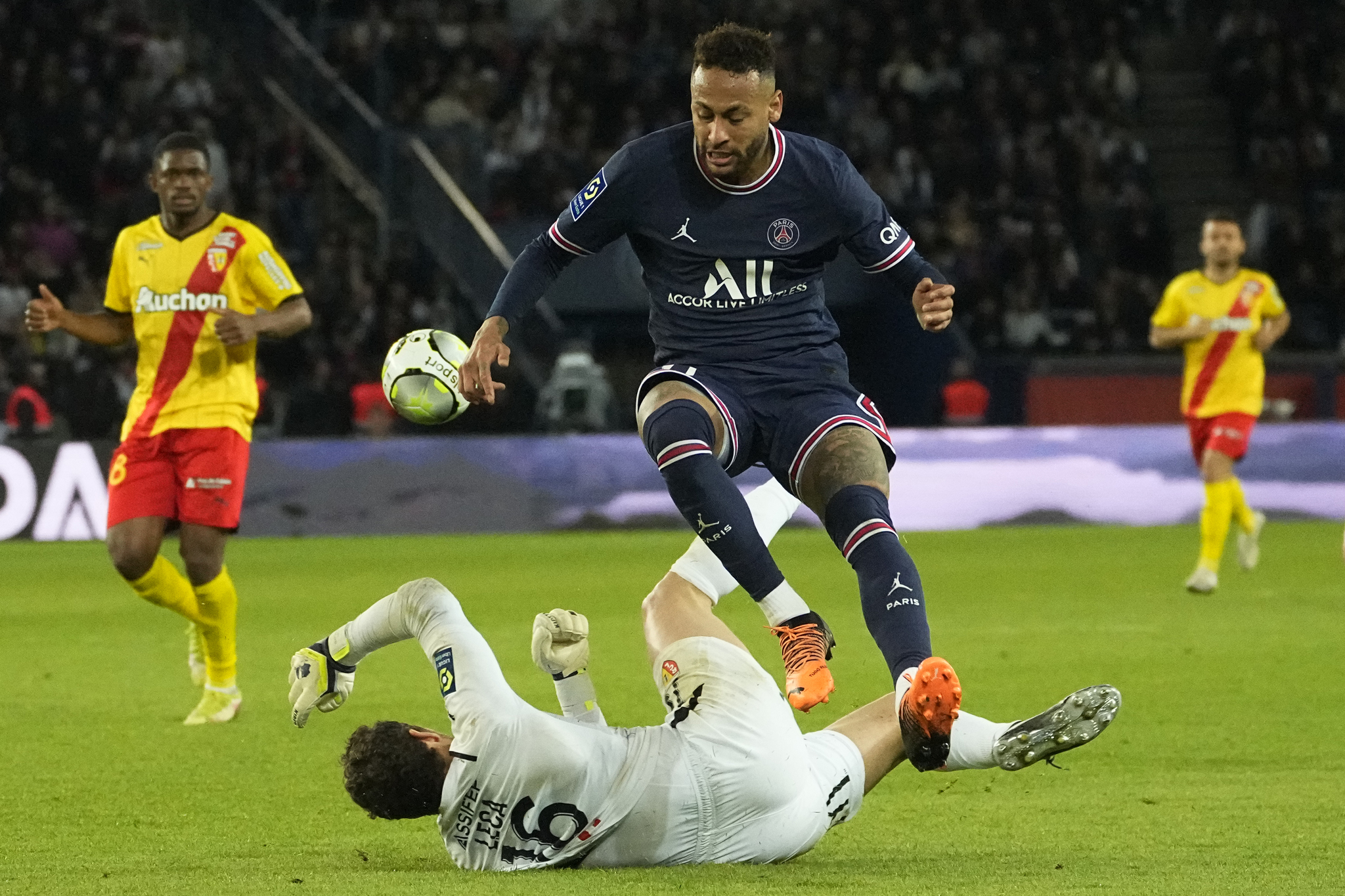 PSG's Neymar, center, and Lens' goalkeeper Jean-Louis Leca challenge for the ball.