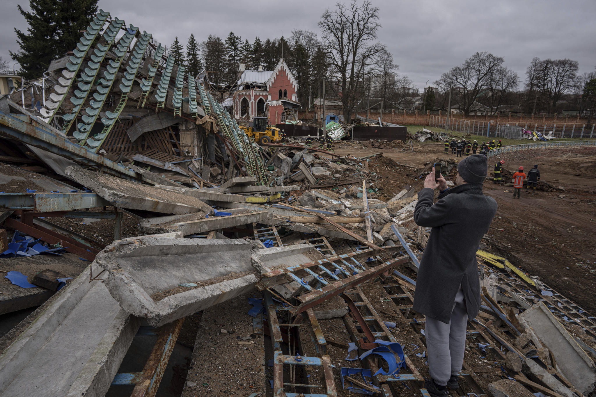 A man takes a picture of a central stadium damaged by Russian forces' shelling in Chernihiv.