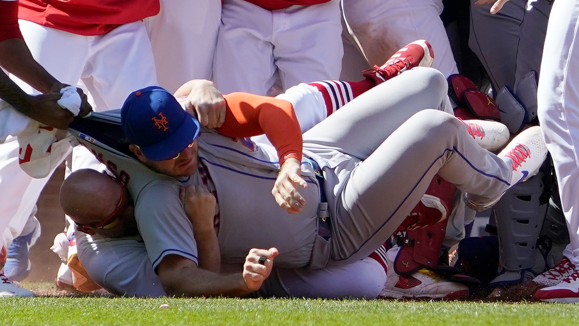 New York Mets' Pete Alonso is taken to the ground by St. Louis Cardinals first base coach Stubby Clapp