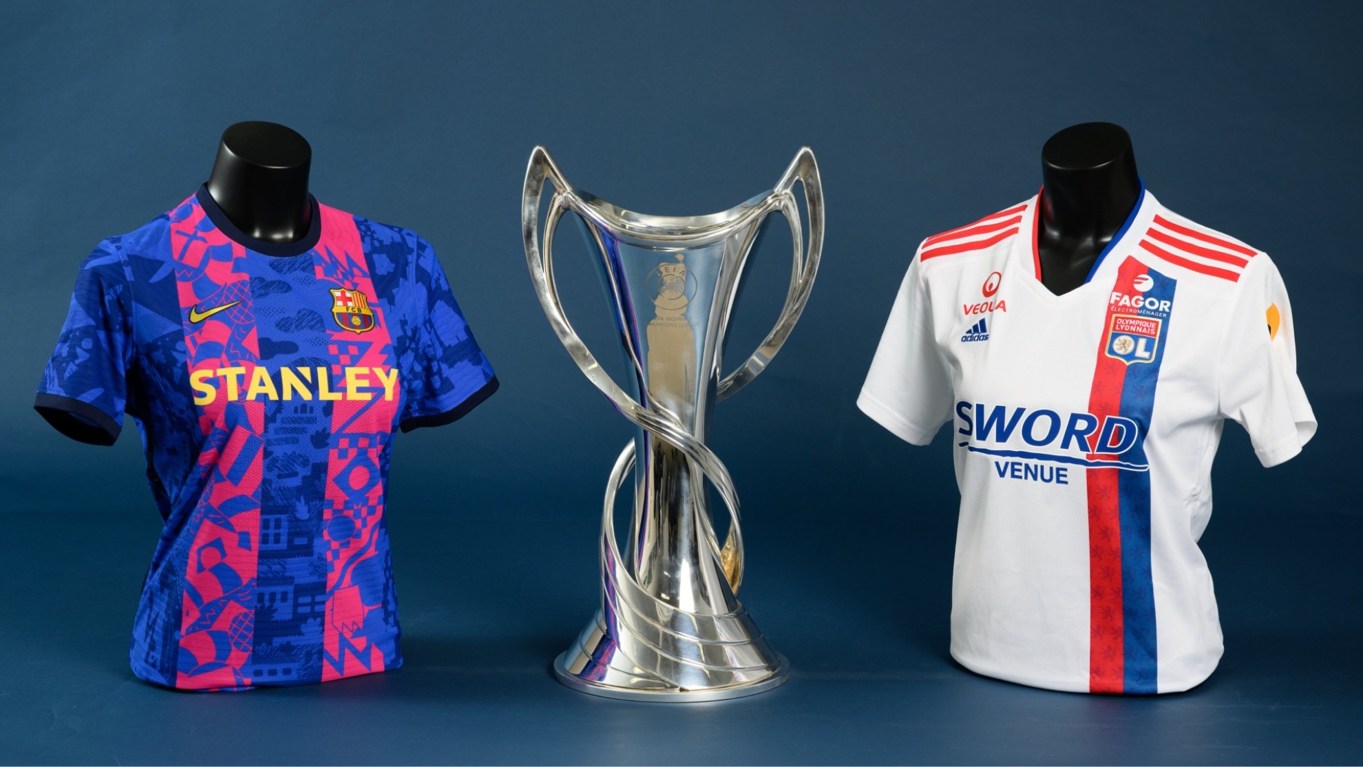 Camisetas de Barcelona y Olympique Lyonnais junto a la copa de campeón de la Champions.