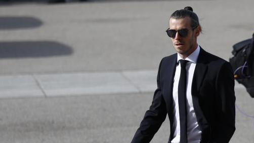 Bale camina con traje y gafas de sol.