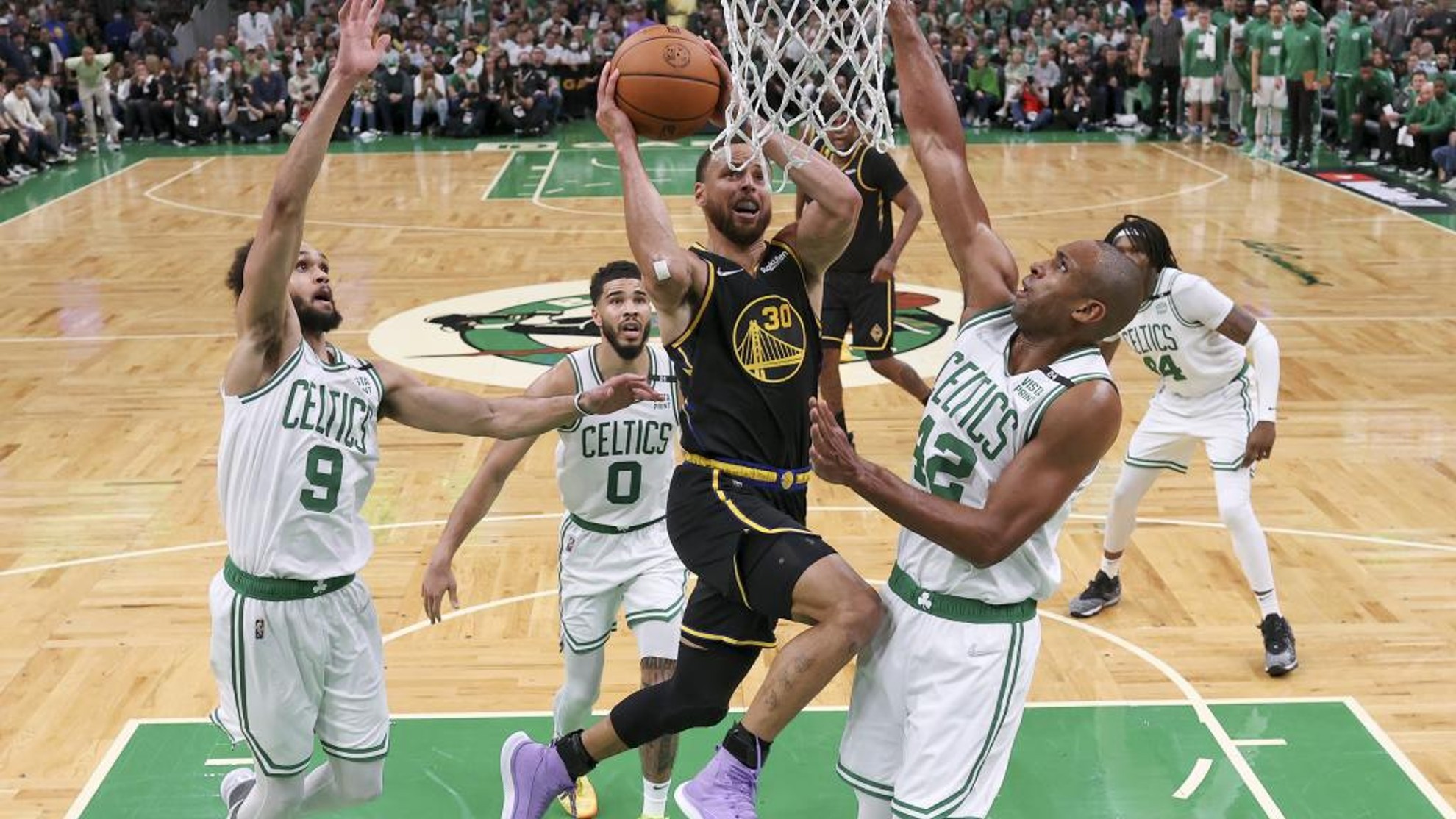 Curry trata de anotar en una penetración rodeado por defensores de los Celtics.