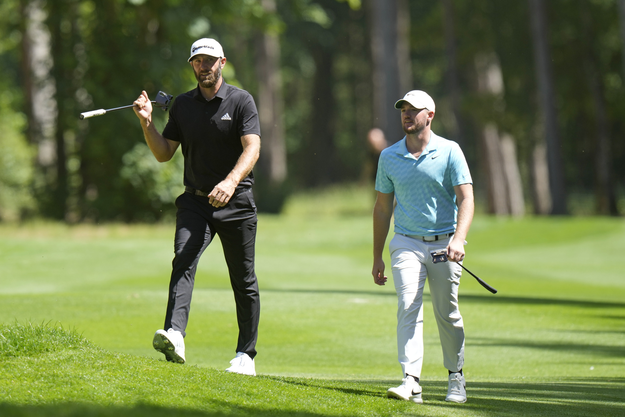 Dustin Johnson and Sam Horsfield walk on the course during the final round of the inaugural LIV Golf Invitational.