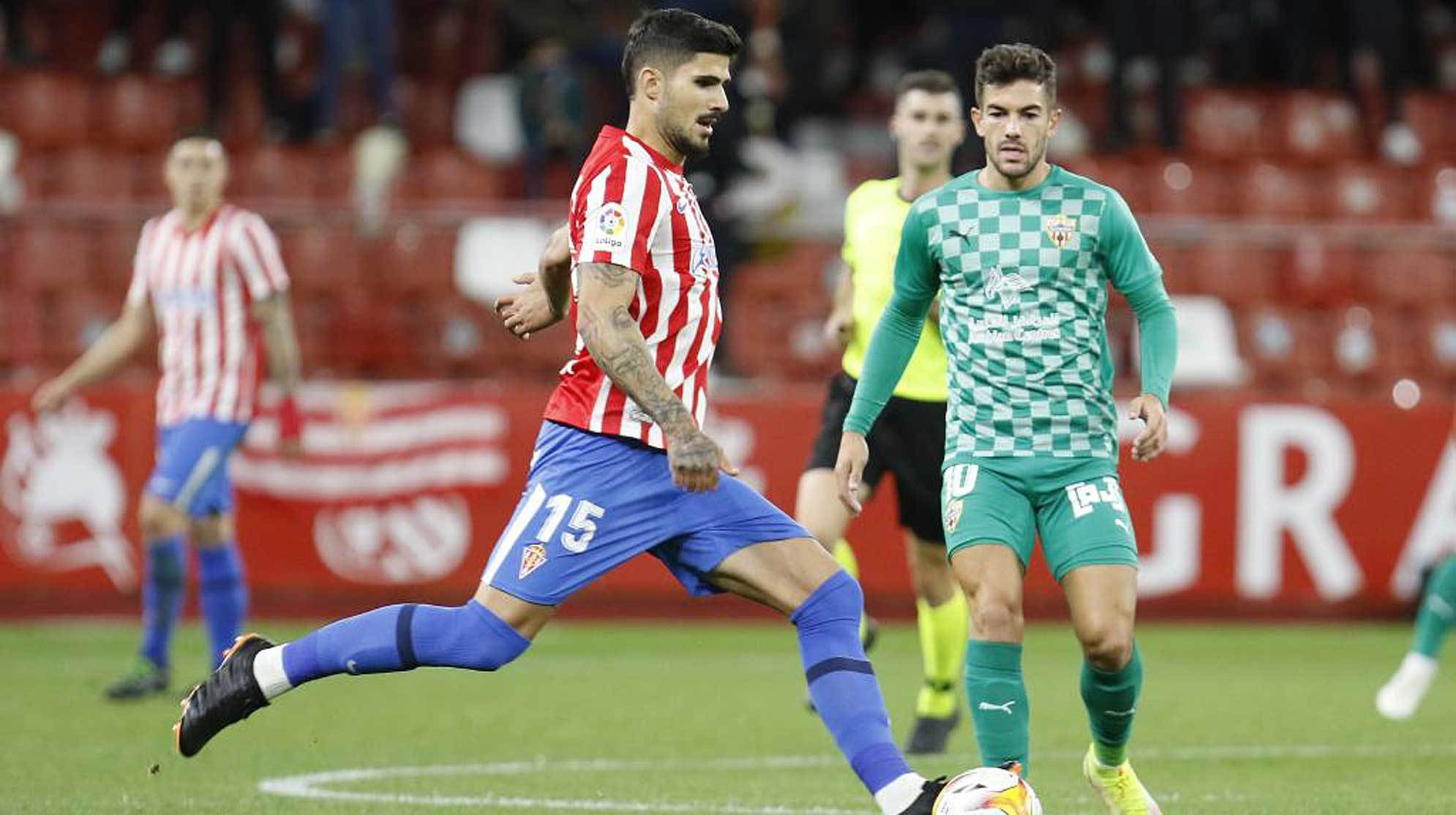 Berrocal golpea al balón en presencia del almeriense Curro Sánchez  en El Molinón