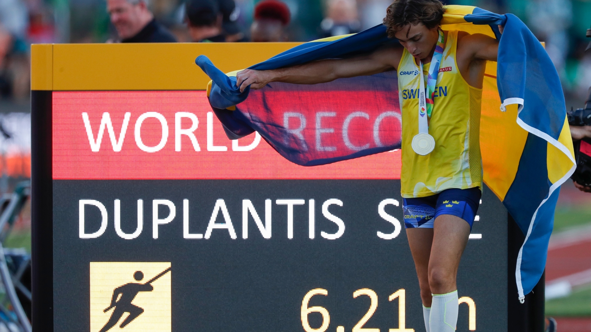Armand Duplantis posa con la bandera sueca delante del nuevo récord mundial. FOTO: EFE