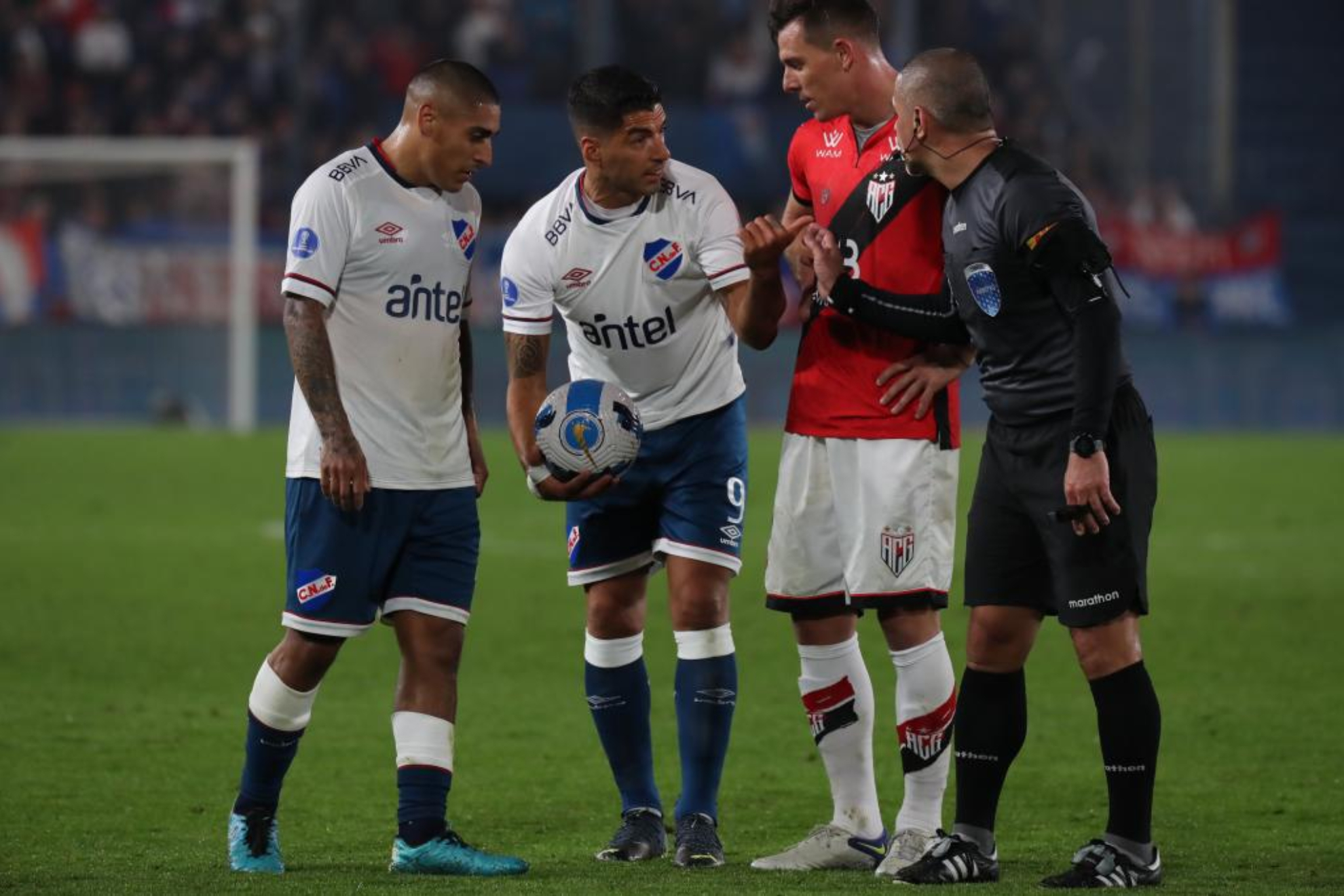 Luis Suárez, balón en mano, habla con el árbitro durante el partido. EFE