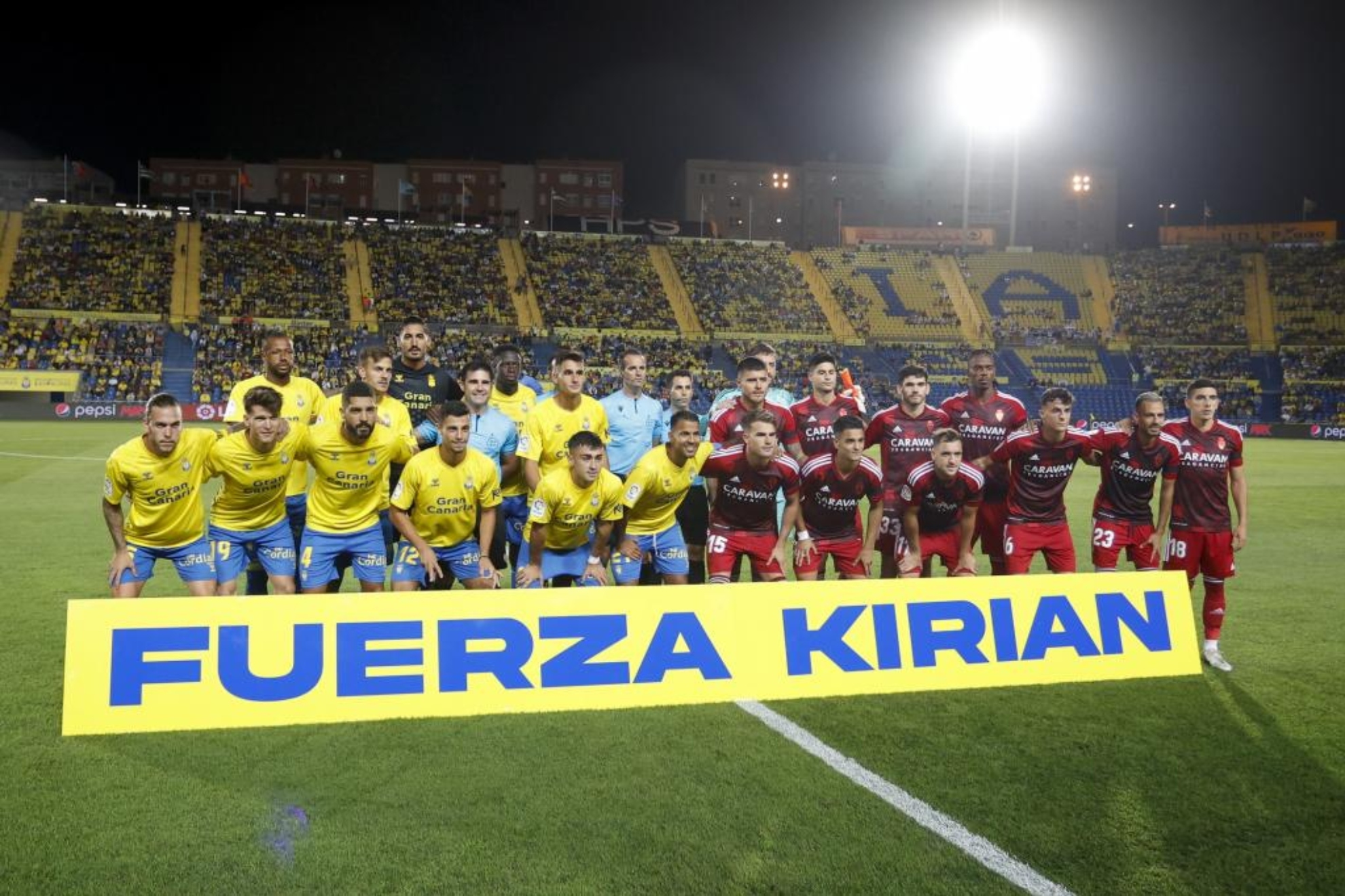 Los jugadores de Las Palmas junto con los del Zaragoza y el cuerpo arbitral homenajean al jugador Kirian/ GERARDO OJEDA