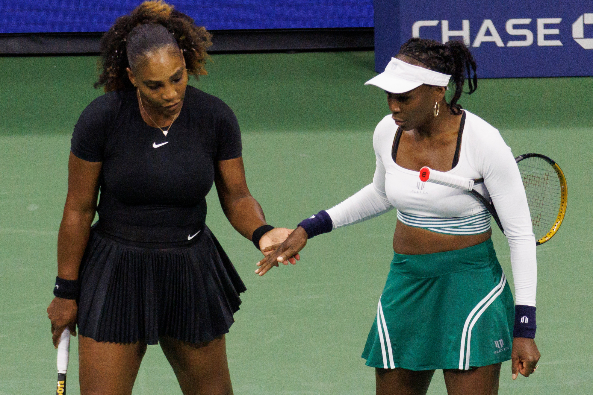 Serena y Venus Williams se saludan tras la derrota en su partido de dobles. EFE