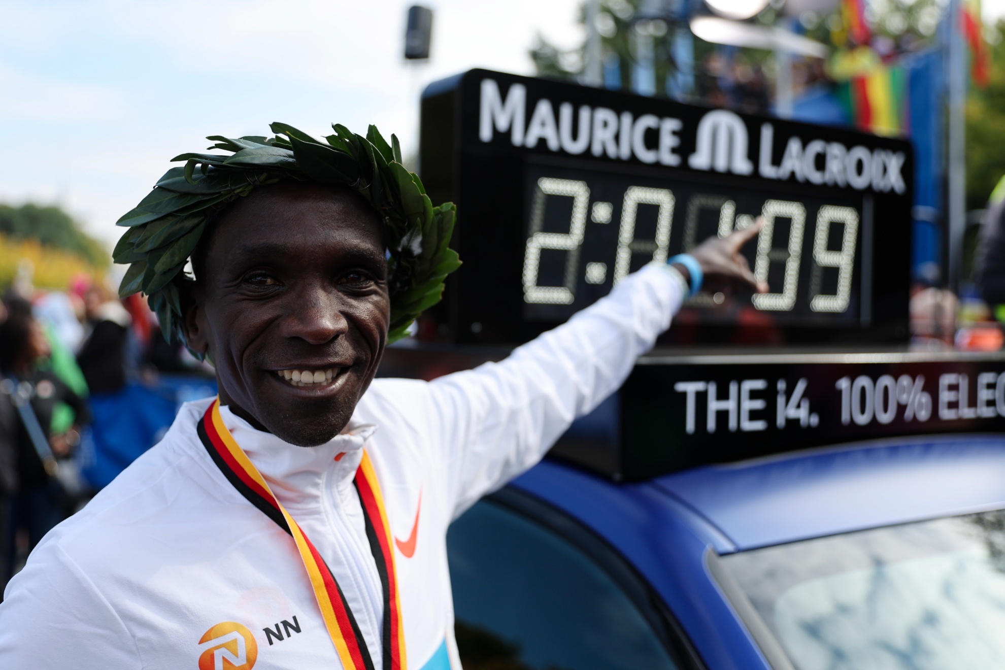 Eliud Kipchoge señala al marcador de un coche de la organización con su nuevo récord del mundo. Foto: AP