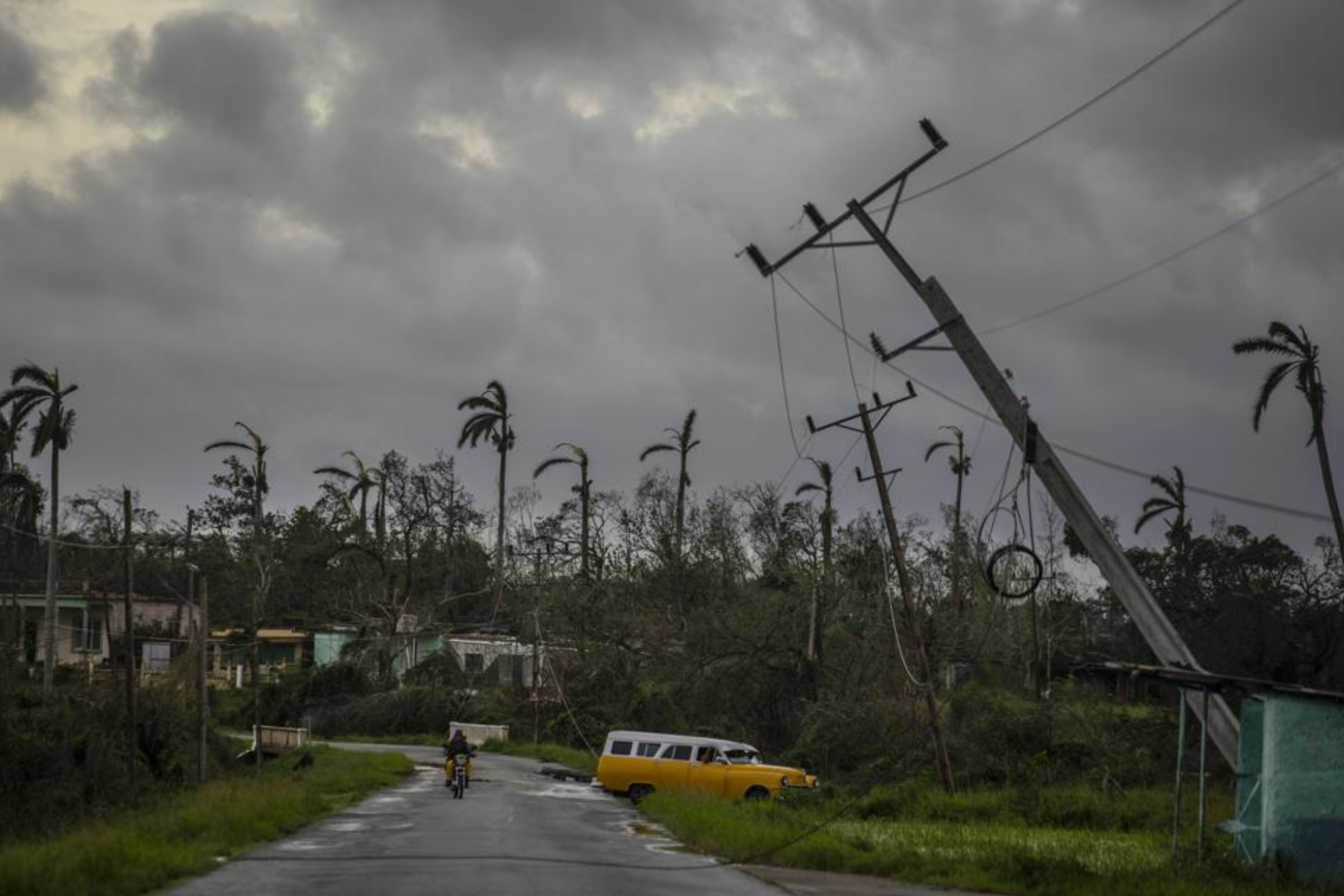 A classic American car drives past utility poles tilted by Hurricane Ian in Pinar del Rio, Cuba. - AP Photo/Ramon Espinosa)
