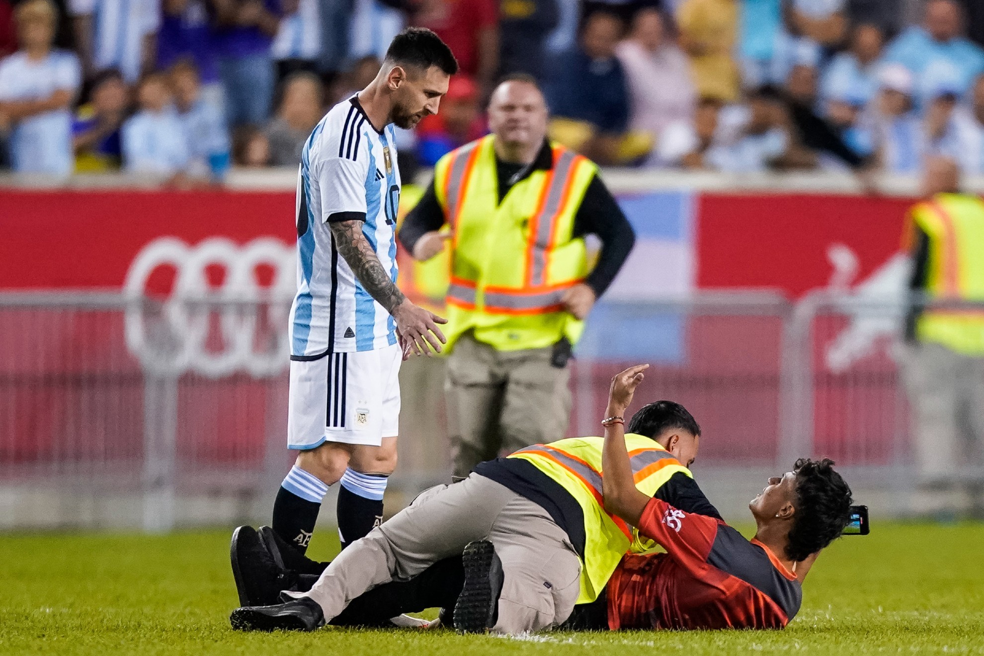 A fan is tackled as he tries to take a picture of Argentina's player Lionel Messi. / AP