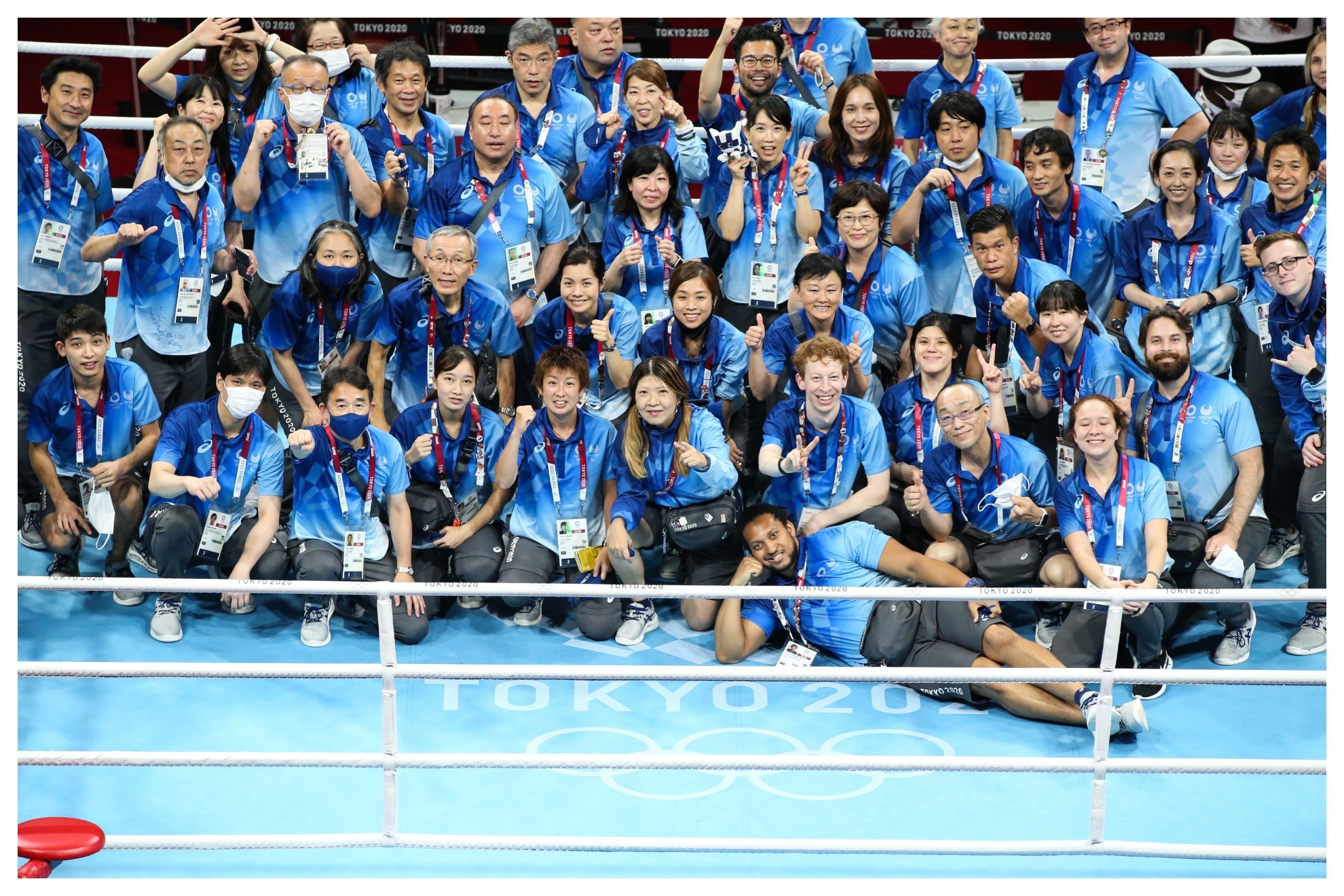 Voluntarios de los Juegos de Tokio posan en el ring a la conclusión de los mismos.
