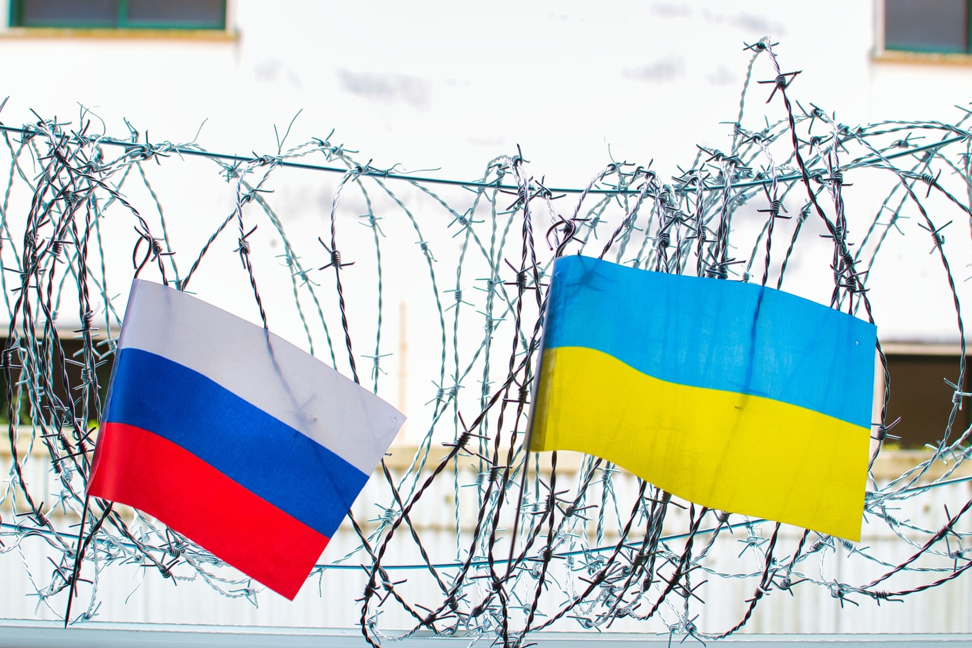 Las banderas de Rusia y Ucrania, sobre una alambrada de espinos.