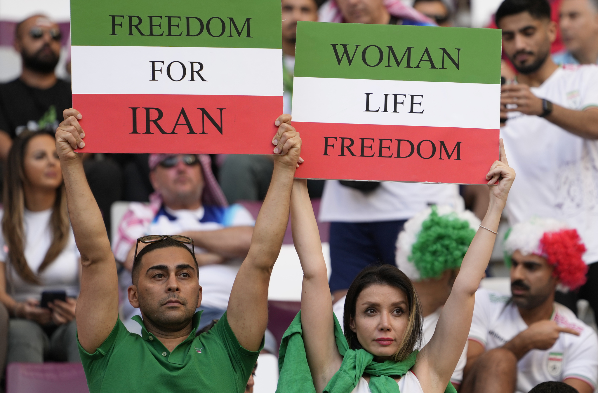 Iranian soccer fans hold up signs reading Woman Life Freedom and Freedom For  lt;HIT gt;Iran lt;/HIT gt;, prior to the World Cup group B soccer match between  lt;HIT gt;England lt;/HIT gt; and  lt;HIT gt;Iran lt;/HIT gt; at the Khalifa International Stadium in in Doha, Qatar, Monday, Nov. 21, 2022. (AP Photo/Alessandra Tarantino)