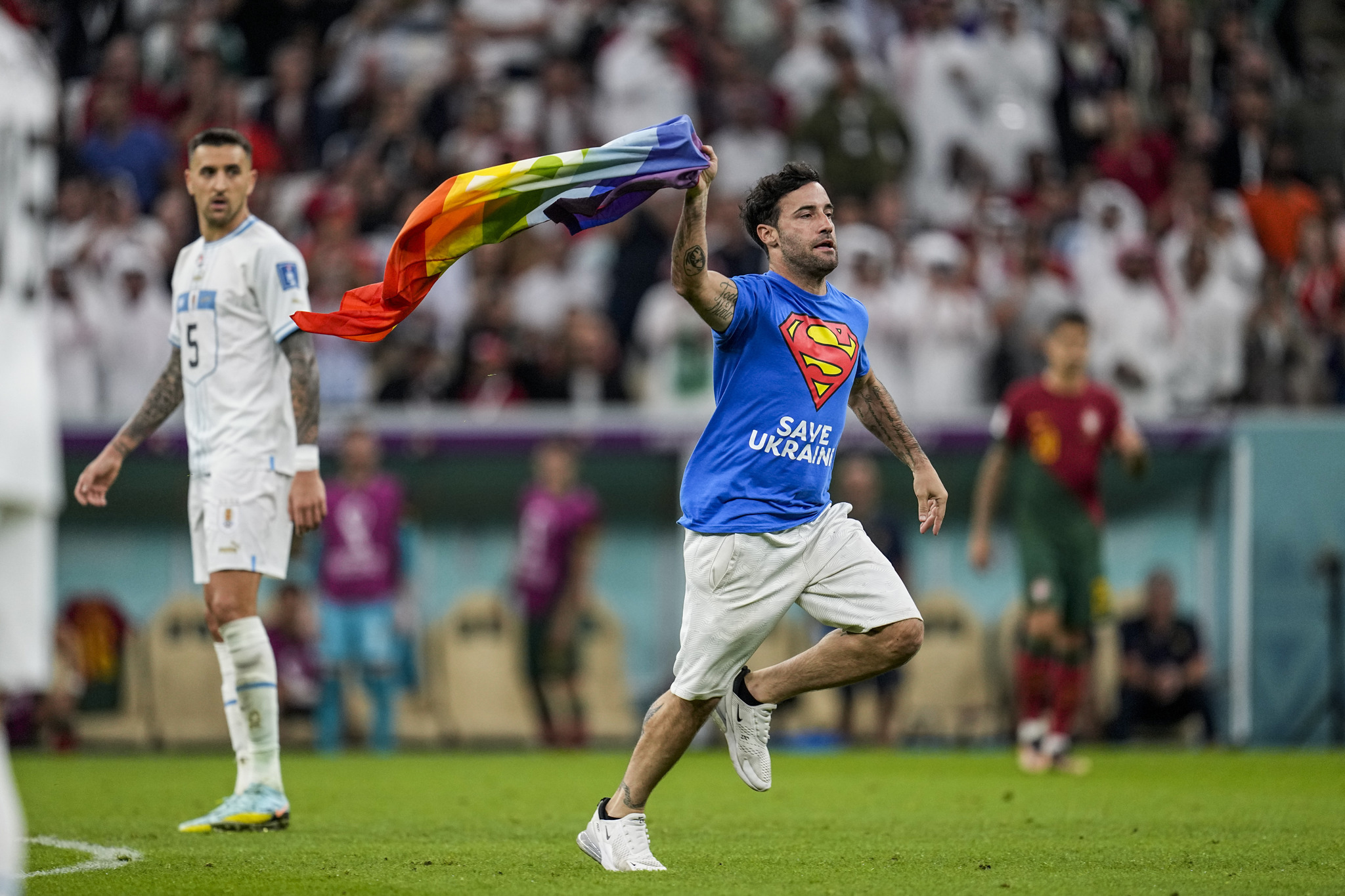 A pitch invader runs across the field with a  lt;HIT gt;rainbow lt;/HIT gt; flag during the  lt;HIT gt;World lt;/HIT gt;  lt;HIT gt;Cup lt;/HIT gt; group H soccer match between Portugal and Uruguay, at the Lusail Stadium in Lusail, Qatar, Monday, Nov. 28, 2022. (AP Photo/Abbie Parr)