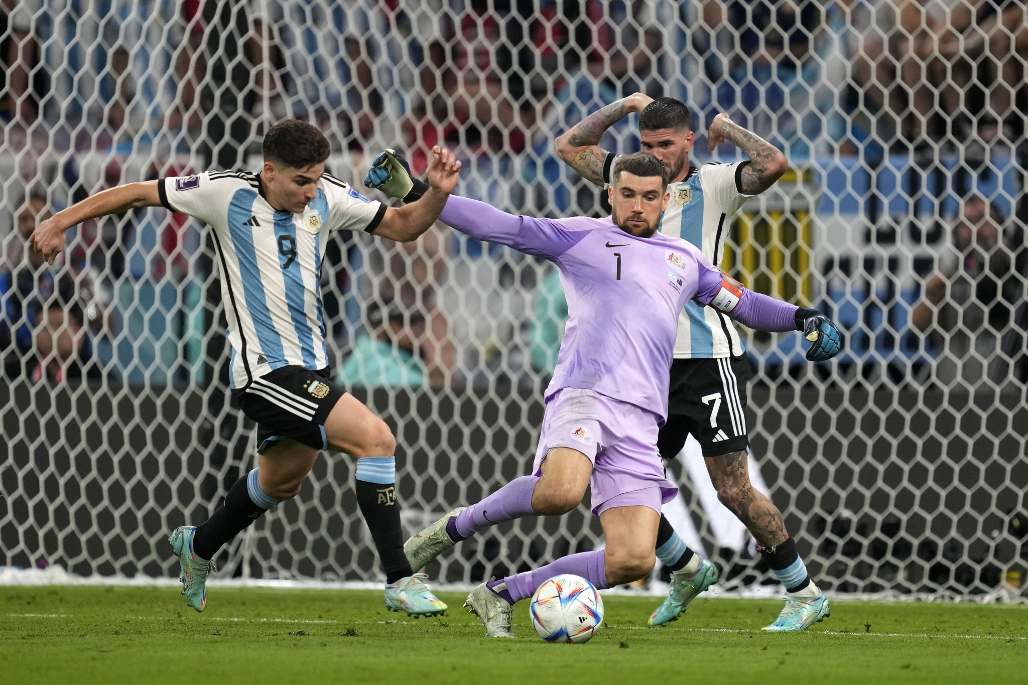Argentina's Julian Alvarez, left, captures the ball beside Australia's goalkeeper Mathew Ryan 