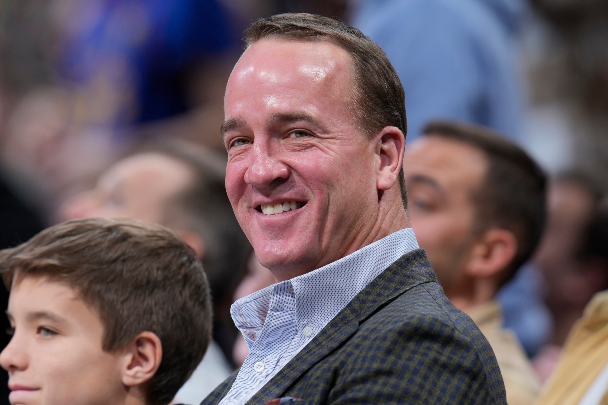 Retired NFL quarterback Peyton Manning smiles for cameras as he is introduced in the first half of an NBA basketball game between the Memphis Grizzlies and the Denver Nuggets