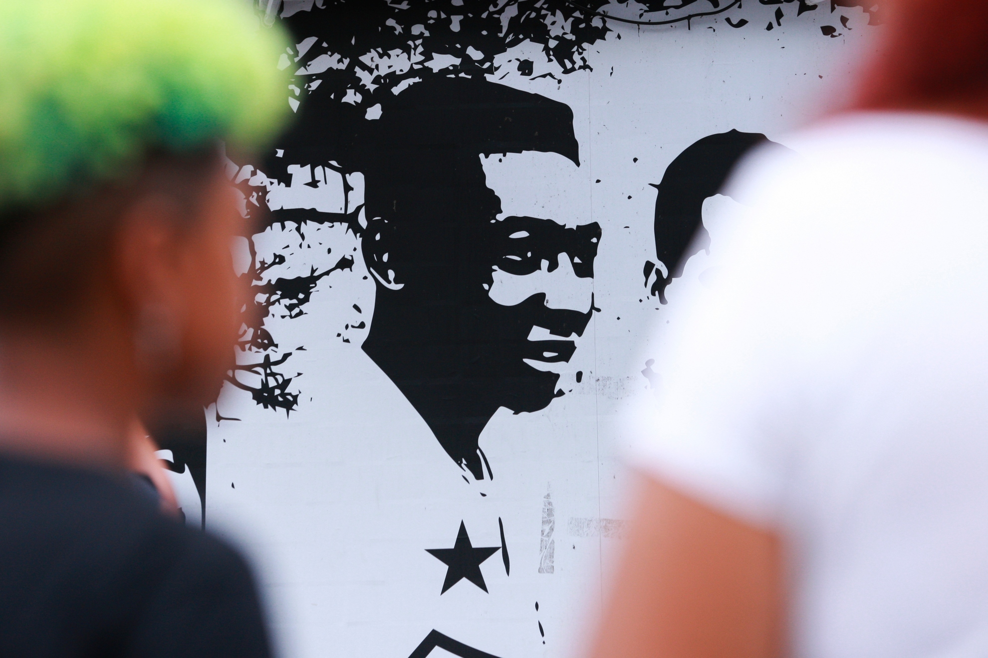 Fans of soccer star Pele walk past mural with an image of the player outside the Vila Belmiro stadium in Santos, Brazil