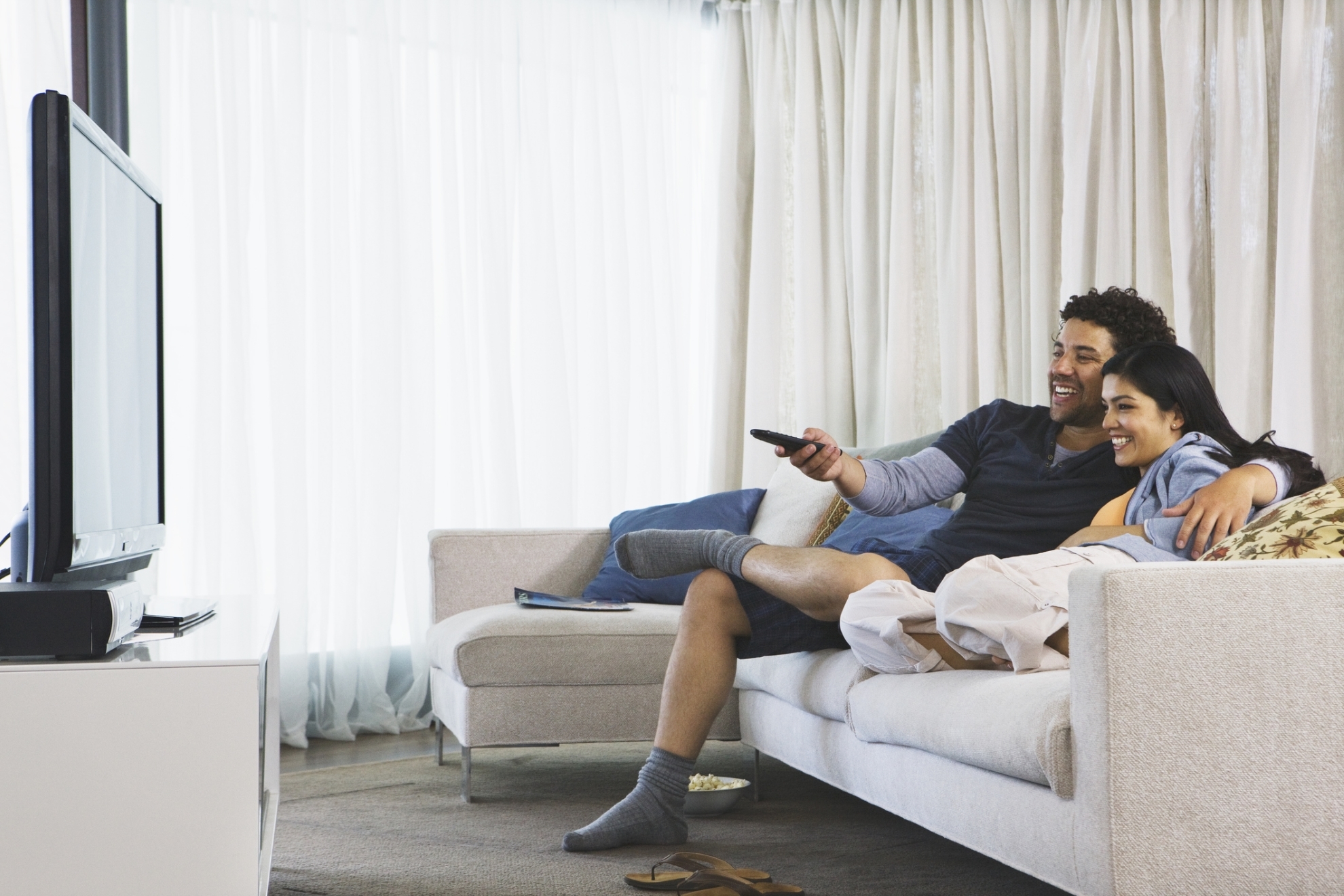Una pareja ve la televisión en su domicilio.