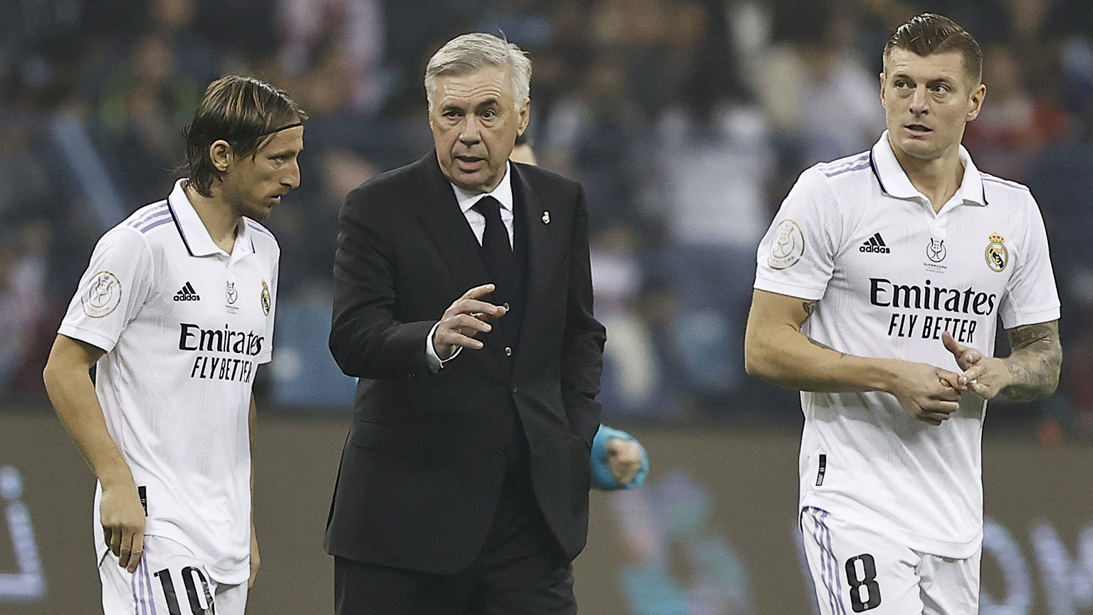 Ancelotti charla con Modric y Kroos durante el descanso de un partido.